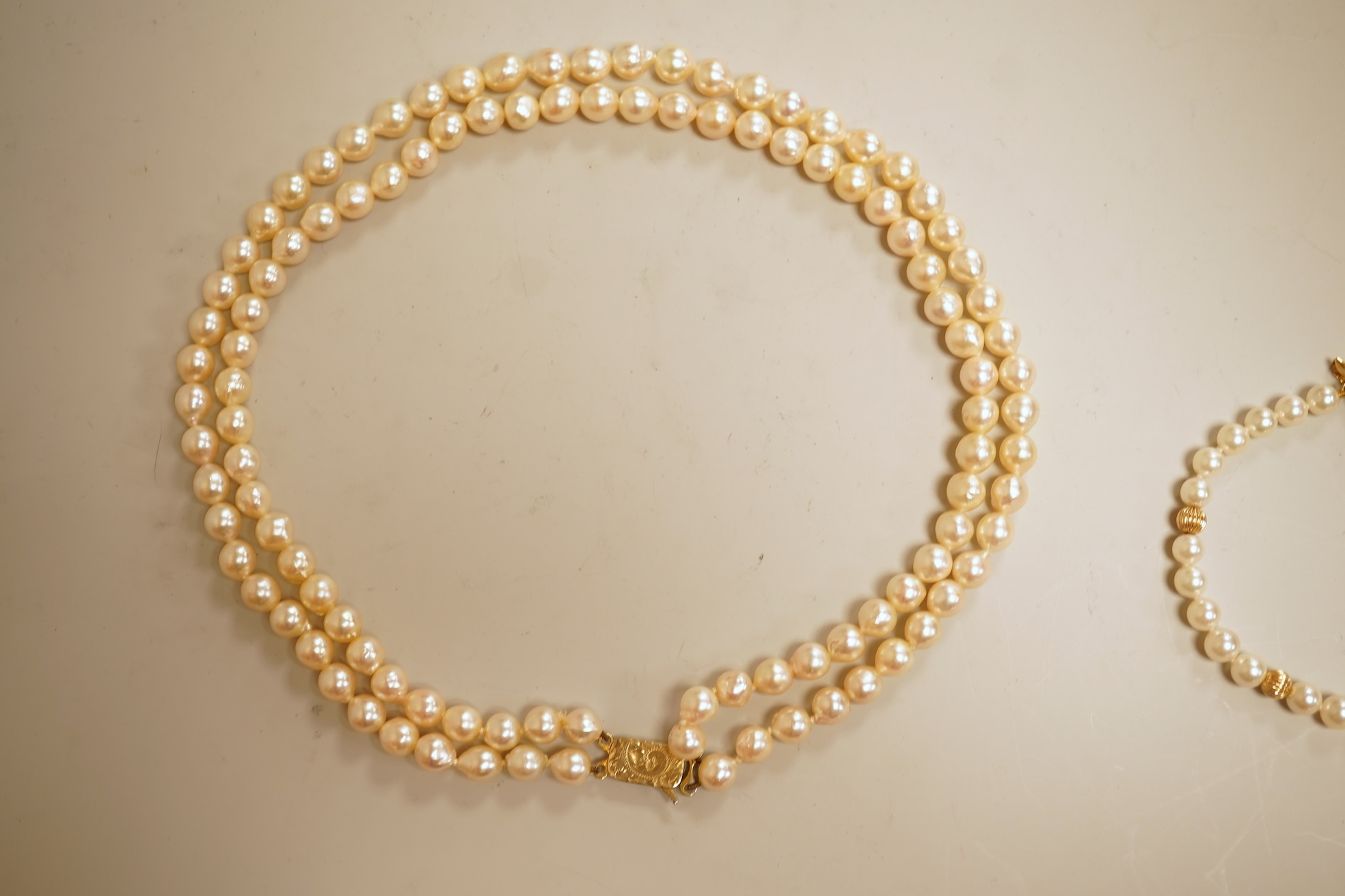 A modern twin strand cultured pearl choker necklace, with an engraved 9ct clasp, approx. 40cm, together with a cultured pearl bracelet, with diamond chip set butterfly shaped 14k clasp, 18cm, with four fluted yellow meta